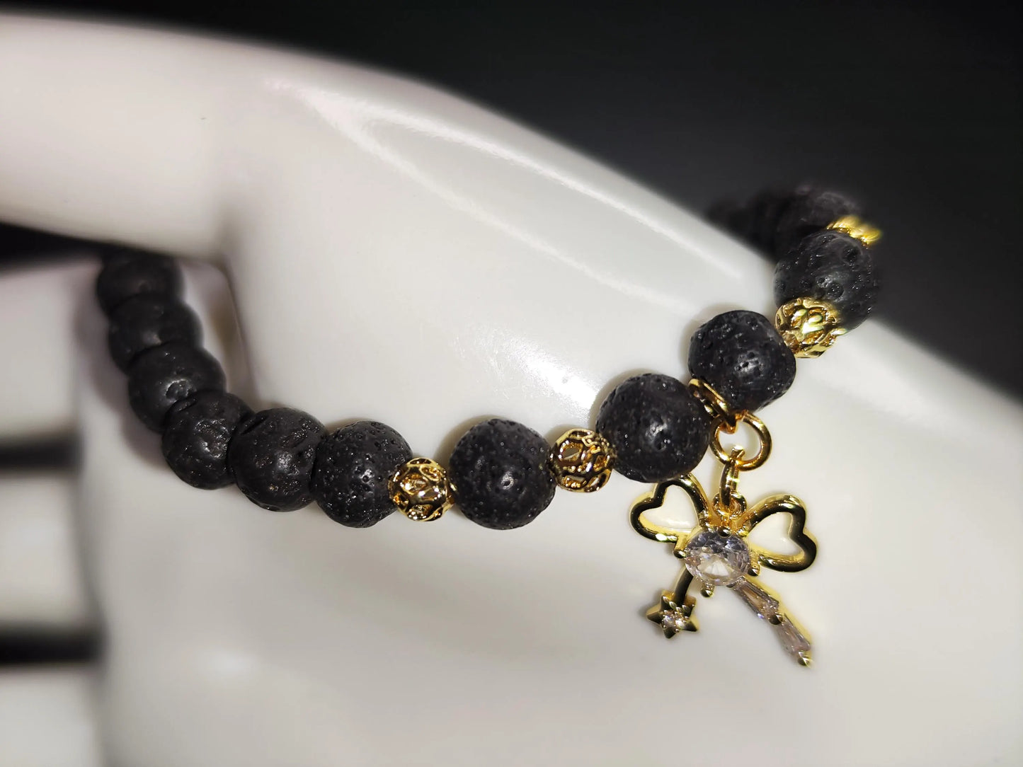 Lava Armband mit 18k vergoldetem Schleifen-Charm – Handgemachtes Schmuckstück für Stärke & Schutz