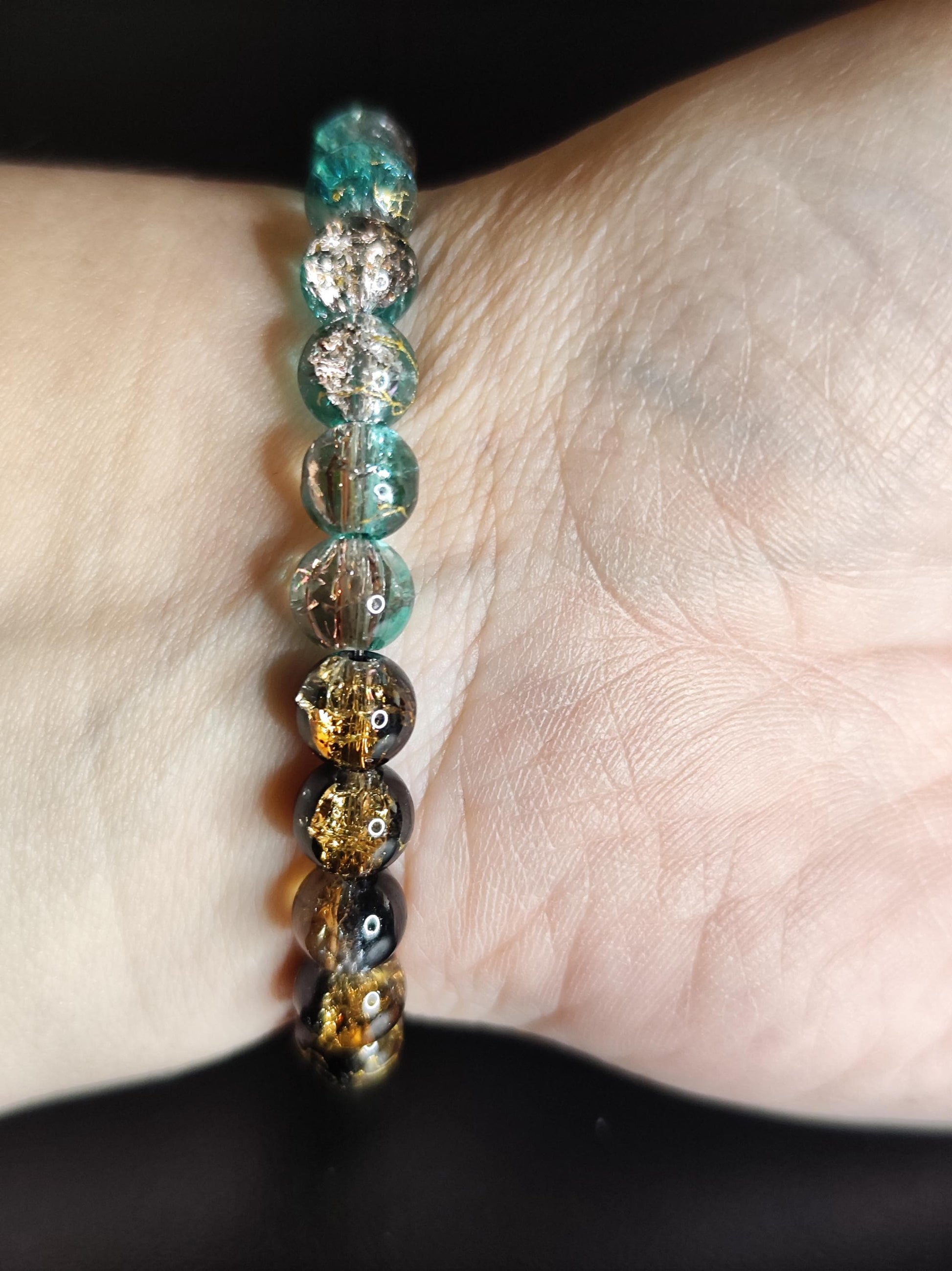 Handgemachtes Armband aus schimmernden Glasperlen mit goldfarbenen Feder-Anhängern – Boho Schmuck – Geschenk für Frauen – Elastisches Armban