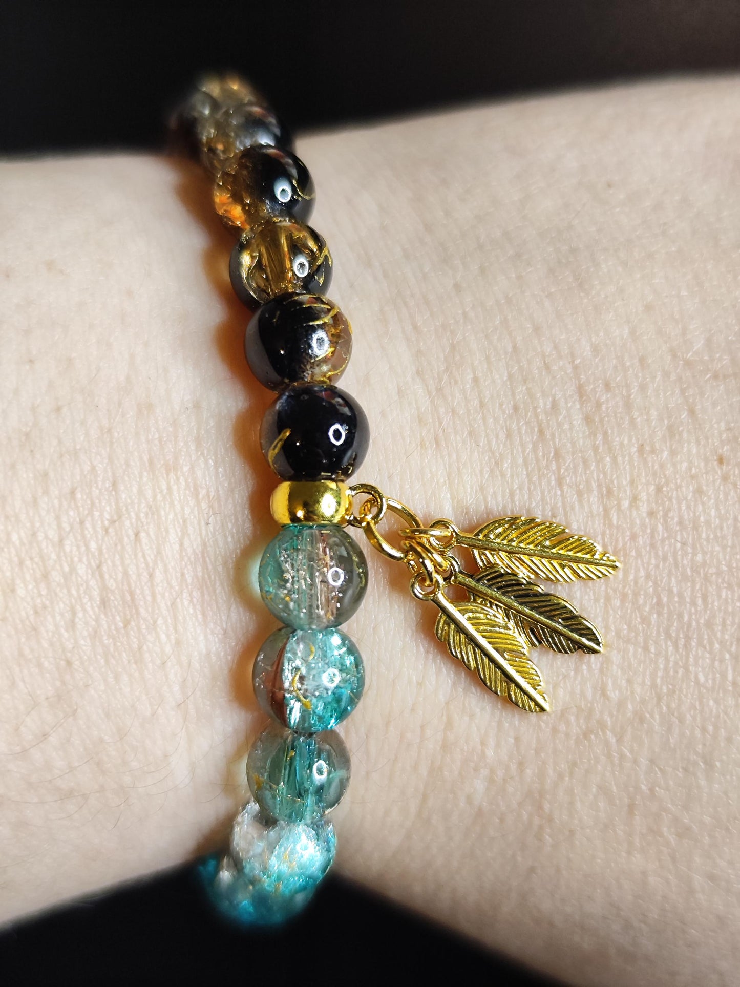 Handgemachtes Armband aus schimmernden Glasperlen mit goldfarbenen Feder-Anhängern – Boho Schmuck – Geschenk für Frauen – Elastisches Armban