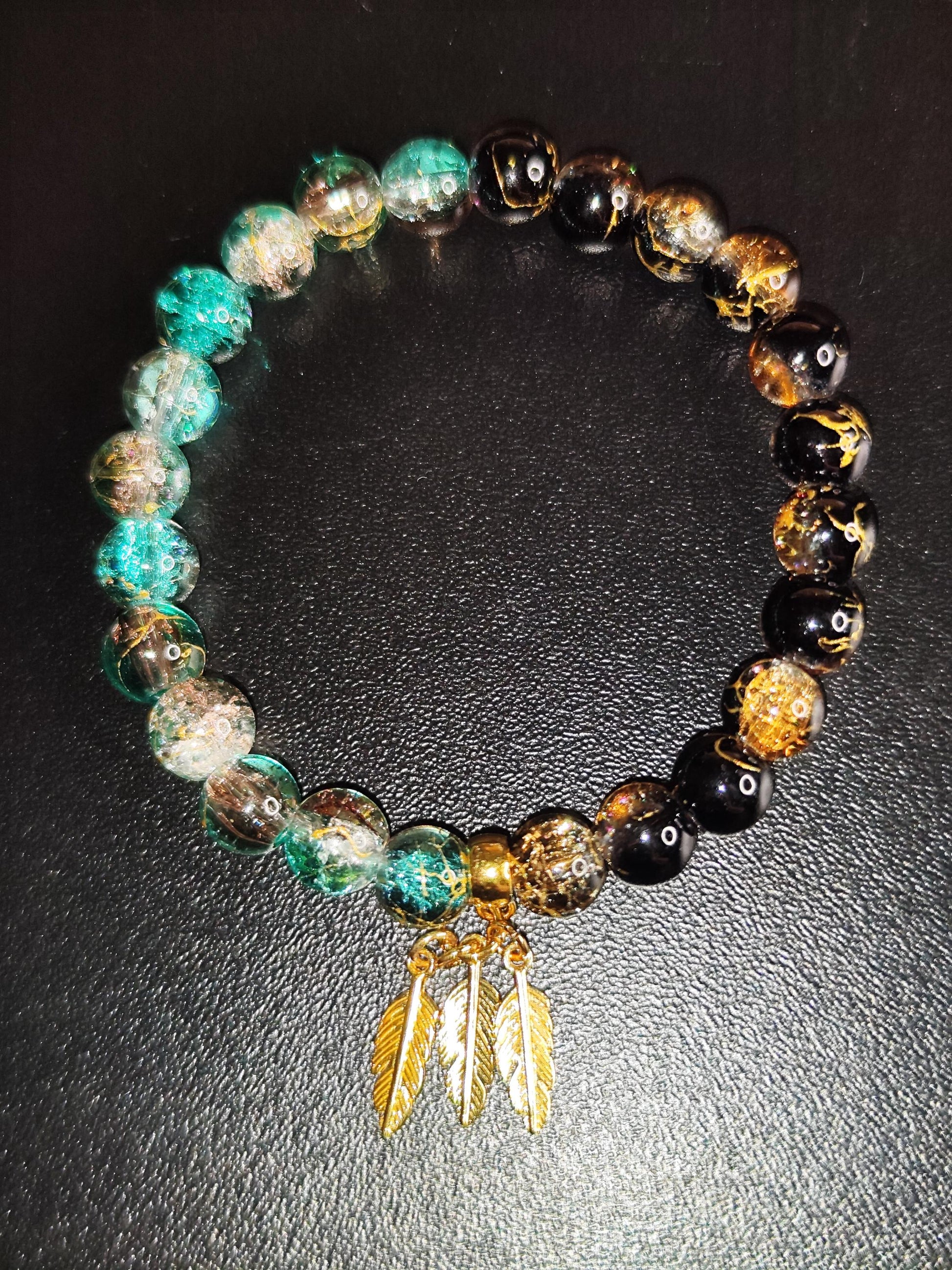 Handgemachtes Armband aus schimmernden Glasperlen mit goldfarbenen Feder-Anhängern – Boho Schmuck – Geschenk für Frauen – Elastisches Armban